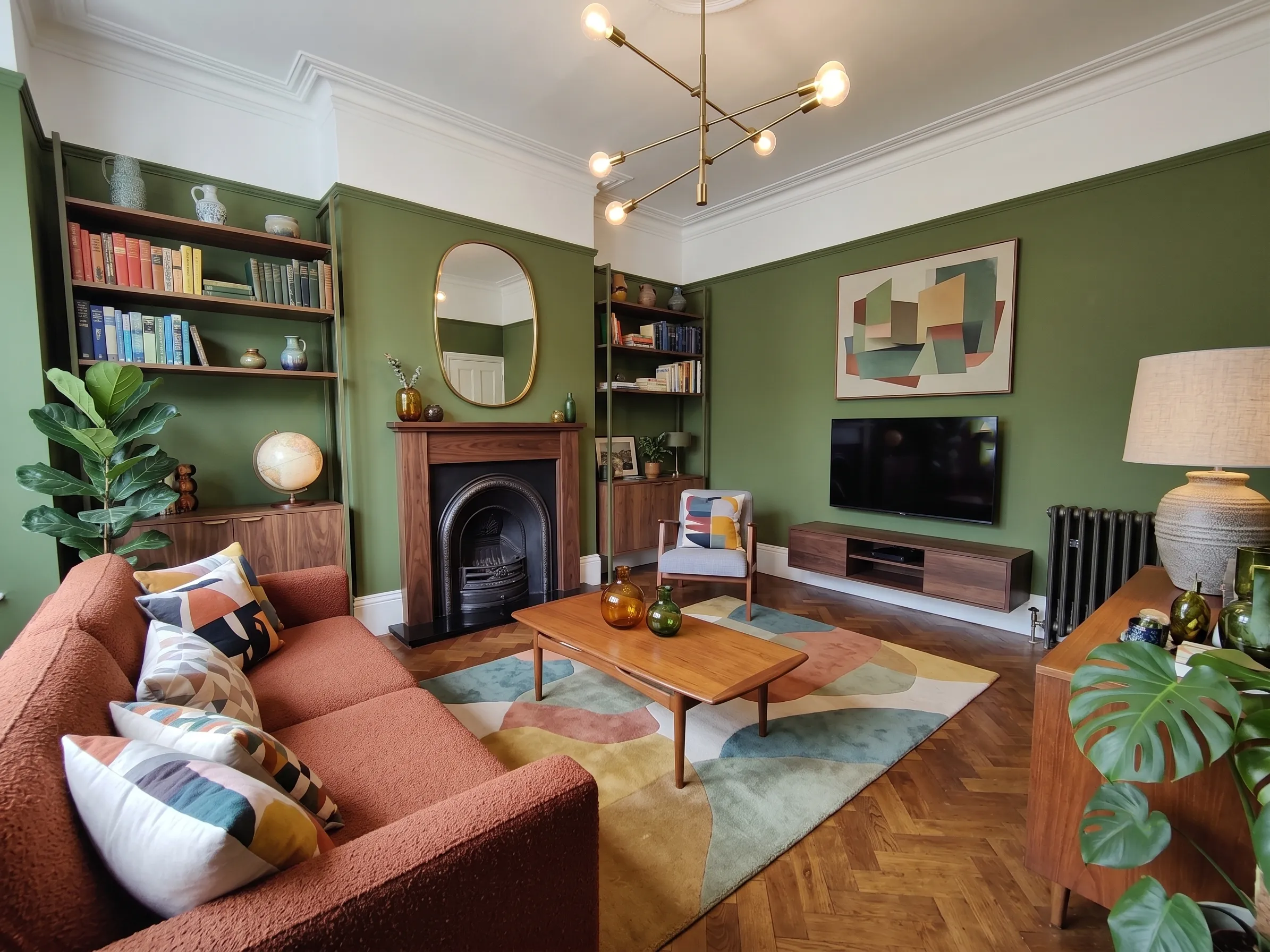 A freshly cleaned living room with sage-green walls, a fireplace, bookshelves and a tidy sofa and coffee table.